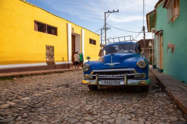 Trinidad, Küba - 12 Haziran 2019: Canlı güneşli gün batımında küçük bir Küba Kasabasının sokaklarında eski bir Klasik Amerikan Arabasının manzarası.