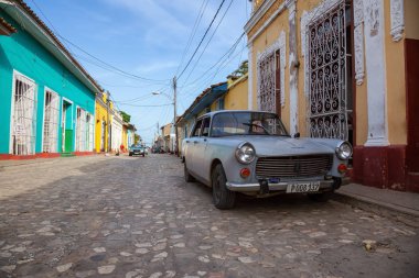 Trinidad, Küba - 12 Haziran 2019: Canlı güneşli gün batımında küçük bir Küba Kasabasının sokaklarında eski bir Klasik Amerikan Arabasının manzarası.