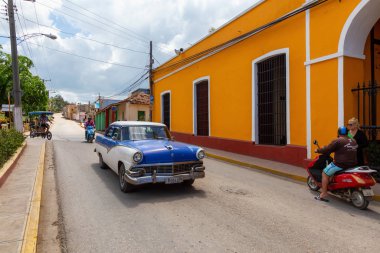 Trinidad, Küba - 6 Haziran 2019: Canlı, güneşli bir günbatımında küçük bir Küba kasabasının sokaklarında eski bir klasik Amerikan arabasının görüntüsü.
