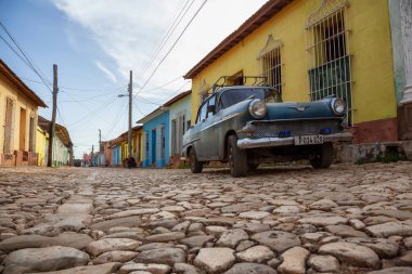Trinidad, Küba - 12 Haziran 2019: Canlı güneşli gün batımında küçük bir Küba Kasabasının sokaklarında eski bir Klasik Amerikan Arabasının manzarası.