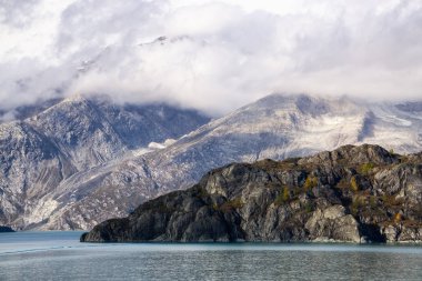 Sonbahar mevsiminde, bulutlu ve renkli bir gündoğumu sırasında okyanus kıyısındaki Amerikan Dağ Manzarası. Buzul Körfezi Ulusal Parkı ve Koruma Alanı, Alaska, Usa.