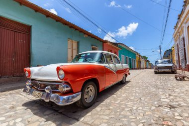 Trinidad, Küba - 9 Haziran 2019: Canlı, güneşli bir günbatımında küçük bir Küba kasabasının sokaklarında eski bir klasik Amerikan arabasının görüntüsü.