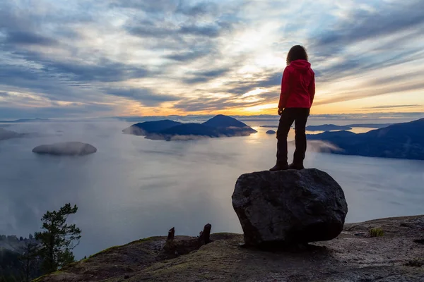 Adventurosa garota no topo de uma montanha durante o pôr do sol — Fotografia de Stock