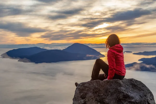 Chica aventurera en la cima de una montaña durante la puesta del sol — Foto de Stock