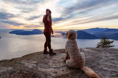 Maceracı Kız bir köpekle dağın tepesinde yürüyüş yapıyor.