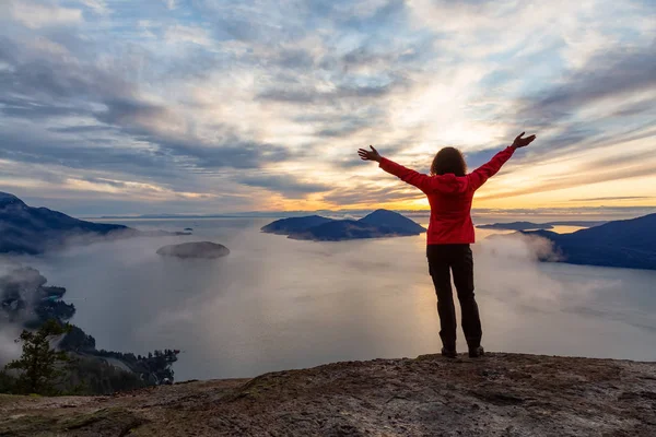 Kalandos lány a hegy tetején naplementekor — Stock Fotó
