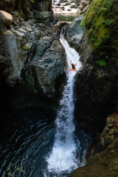 Äventyrlig man rider den naturliga vattenrutschbanan på vattenfallet — Stockfoto