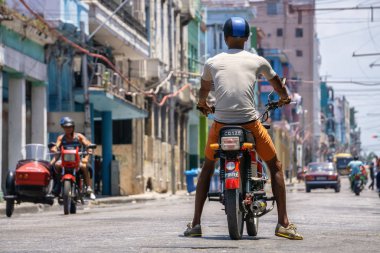 Eski Havana şehrinin sokaklarında motosikletli Kübalı adamlar