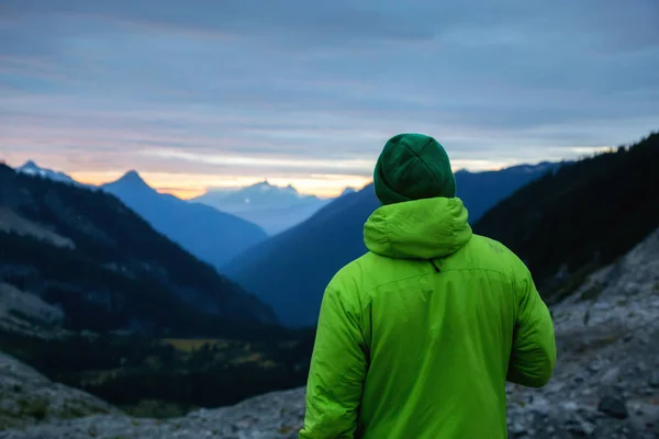 緑のジャケットを着た冒険的な男は、カナダの山の風景の美しい自然の景色を楽しんでいます — ストック写真