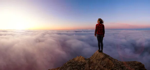 Äventyrlig flicka på ett stenigt berg ovanför molnen — Stockfoto