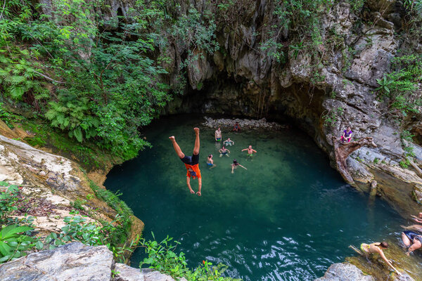 People enjoying a beautiful water pond by the waterfall in a canyon.
