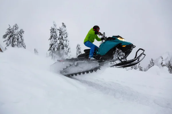 白雪の中でスノーモービルに乗る冒険的な男 — ストック写真