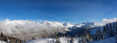 Whistler, British Columbia, Kanada. Bulutlu ve güneşli bir kış gününde Kanada Karla kaplı arka planda Blackcomb Dağı manzarası.