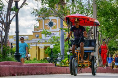 Trinidad, Küba - 11 Haziran 2019: Canlı güneşli bir günde küçük bir Küba kasabasının sokaklarında bisiklet süren adam.