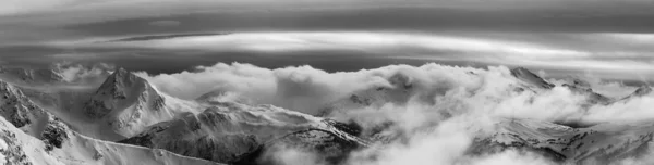 ウィスラー ブリティッシュコロンビア州 カナダ 曇り空と鮮やかな冬の夕日の間にカナダの雪に覆われた山の風景の美しいパノラマビュー 黒と白 — ストック写真