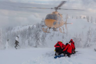 Kuzey Vancouver, British Columbia, Kanada. Kuzey Kıyısı Arama Kurtarma Ekibi Seymour Dağı 'nda kışın gün batımında helikopterle kayakçı bir adamı kurtarıyor..