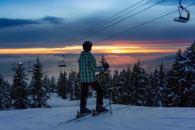 Neşeli ve güneşli kış günbatımında güzel bir karlı dağda kayak yapan maceraperest kız. Seymour, North Vancouver, British Columbia, Kanada 'da çekildi.