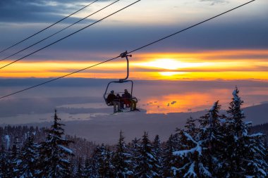Seymour Dağı, Kuzey Vancouver, Britanya Kolumbiyası, Kanada - 10 Şubat 2020 - Güneşli ve bulutlu kış günbatımında bir kayak merkezinin tepesine çıkmak.