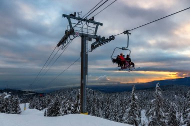 Seymour Dağı, Kuzey Vancouver, Britanya Kolumbiyası, Kanada - 12 Şubat 2020 - Güneşli ve bulutlu kış günbatımında bir kayak merkezinin tepesine çıkmak.