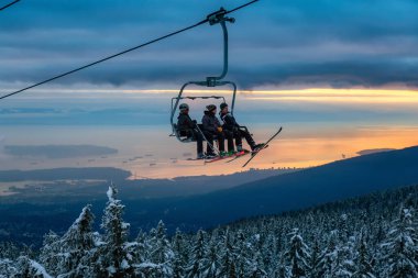 Seymour Dağı, Kuzey Vancouver, Britanya Kolumbiyası, Kanada - 12 Şubat 2020 - Güneşli ve bulutlu kış günbatımında bir kayak merkezinin tepesine çıkmak.