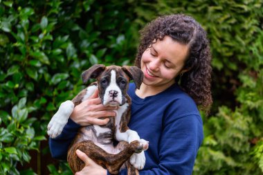 Bahçesinde küçük şirin bir boksör köpeği olan beyaz, beyaz, beyaz bir kadın. Vancouver, British Columbia, Kanada 'da çekildi..
