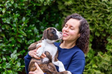 Bahçesinde küçük şirin bir boksör köpeği olan beyaz, beyaz, beyaz bir kadın. Vancouver, British Columbia, Kanada 'da çekildi..