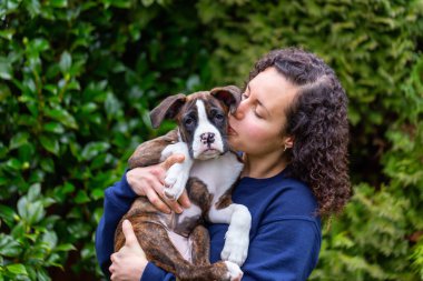 Bahçesinde küçük şirin bir boksör köpeği olan beyaz, beyaz, beyaz bir kadın. Vancouver, British Columbia, Kanada 'da çekildi..
