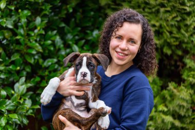 Bahçesinde küçük şirin bir boksör köpeği olan beyaz, beyaz, beyaz bir kadın. Vancouver, British Columbia, Kanada 'da çekildi..