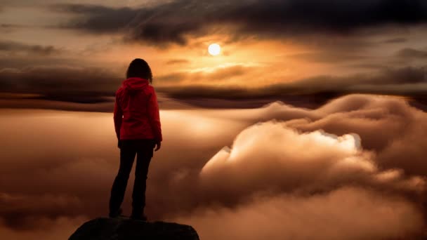 Cinemagraph of Girl on a Rocky Peak with clouds below — Stock video