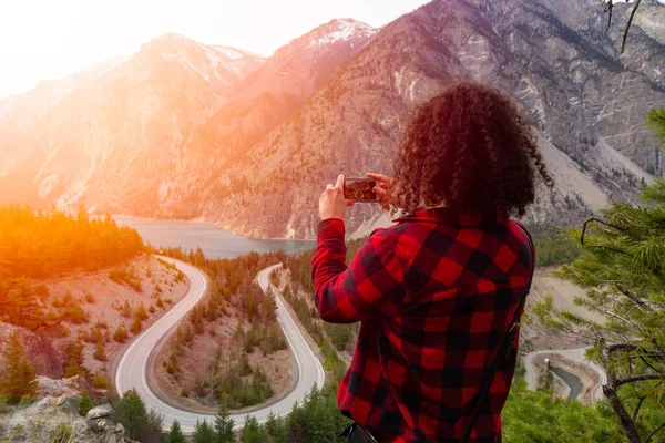 Äventyrlig flicka som tar bilder av en naturskön väg i Kanadas bergslandskap — Stockfoto