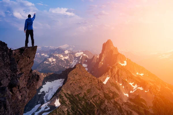 Adventurous Man Hiker With Hands Up on top of a Steep Rocky Cliff. — Stock Photo, Image