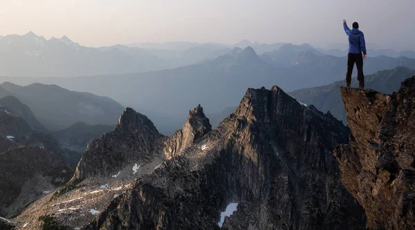 Adventurous Man Hiker With Hands Up on top of a Steep Rocky Cliff. — Stock Photo, Image