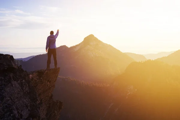 Hombre aventurero excursionista con las manos arriba en la cima de un acantilado rocoso empinado. —  Fotos de Stock