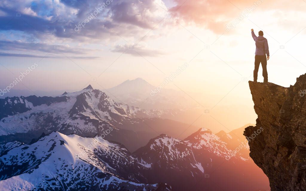 Adventurous Man Hiker With Hands Up on top of a Steep Rocky Cliff