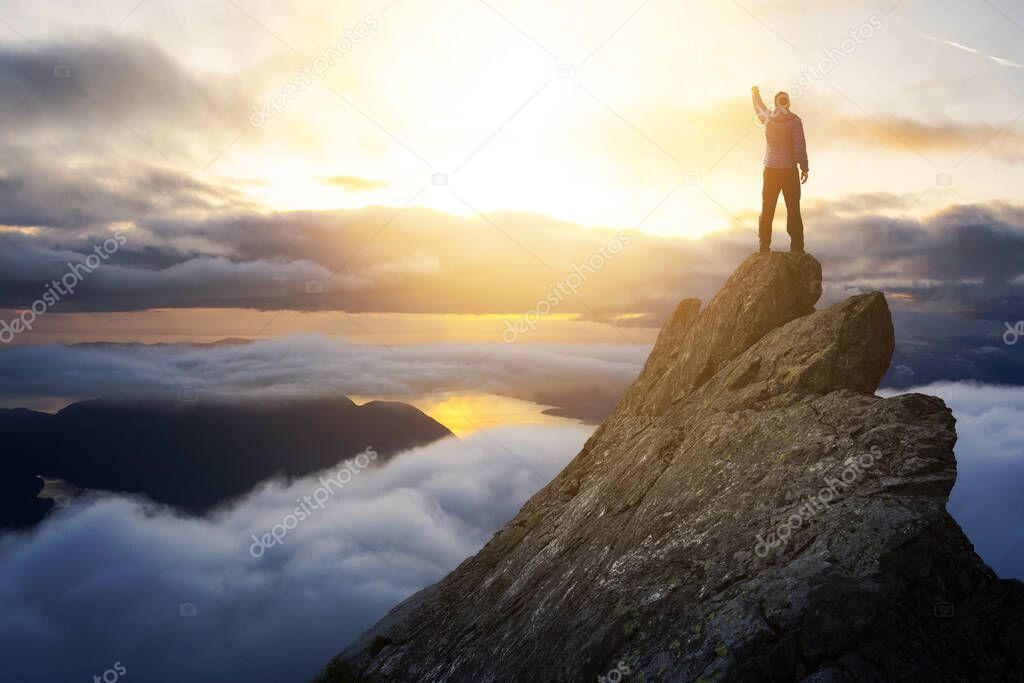 Adventurous Man Hiker With Hands Up on top of a Steep Rocky Cliff.