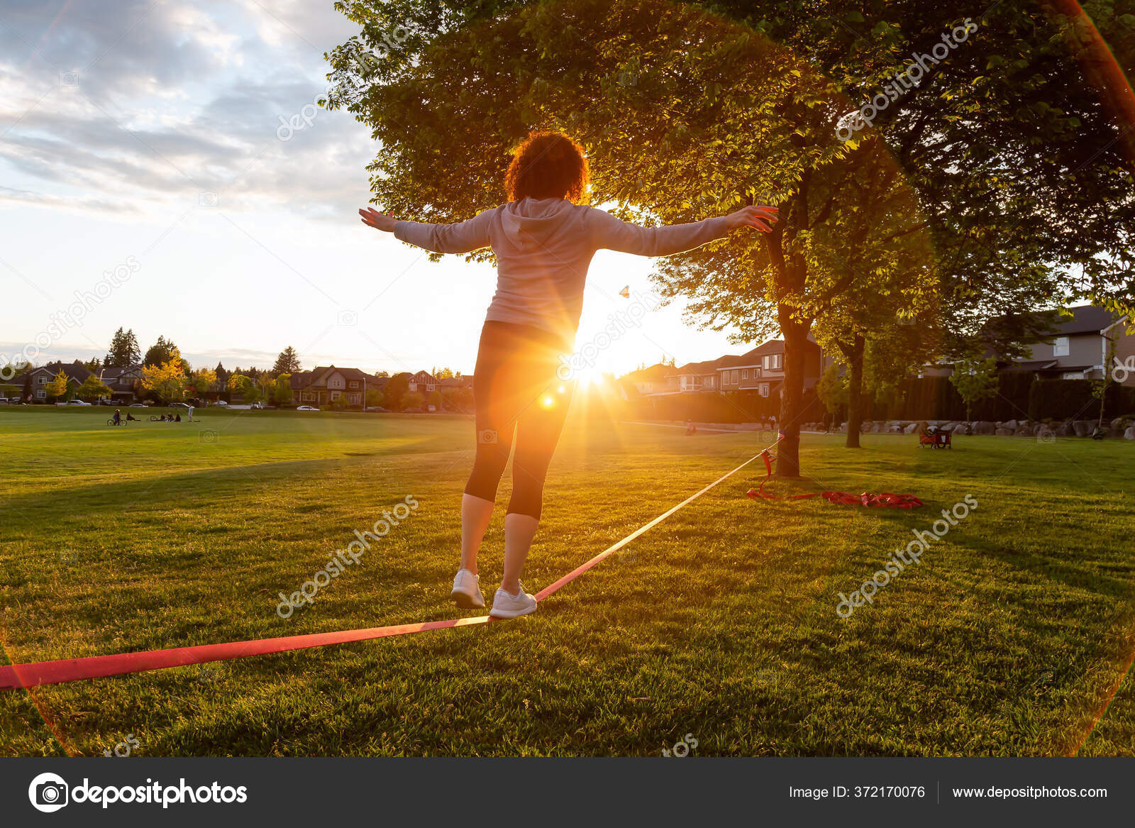 Girl walking on a Slackline in a park during a sunny sunset. Stock
