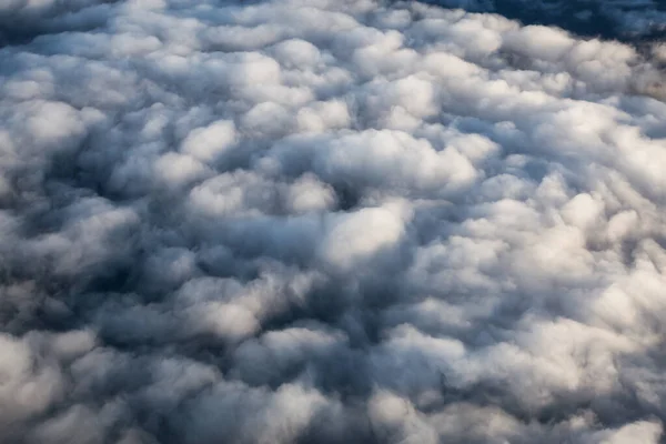 Güneşli bir gündoğumu sırasında beyaz ve kabarık bulutların üzerinden hava manzarası. — Stok fotoğraf