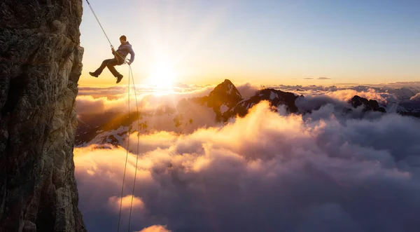 Epic Adventurous Extreme Sport Composite of Rock Climbing Man Rappelling from a Cliff. — Stock Photo, Image