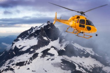 Sarı helikopter Rocky Dağları üzerinde uçuyor.