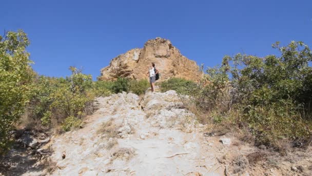 年轻女孩旅游。干沙漠山。一个女孩站在顶部，喜欢攀爬。在山顶上休息。底部视图 — 图库视频影像