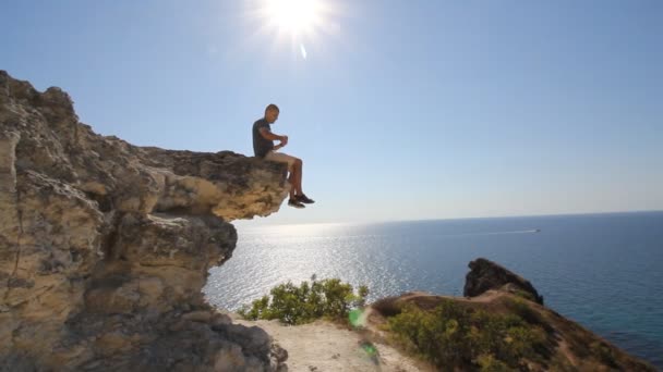 Young Climber es fotografiado en la cima de una montaña. Vista al mar. Cielo Azul. Emociones agradables de vacaciones de verano extremas — Vídeos de Stock