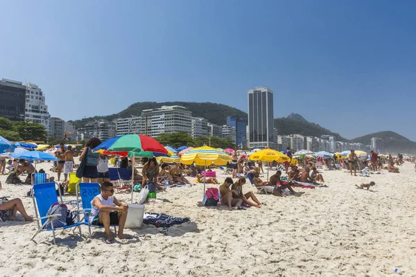Guarda-chuvas de praia e pessoas desfrutando de um dia ensolarado — Fotografia de Stock