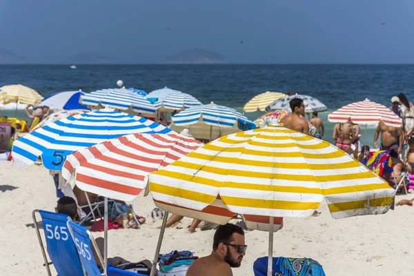 Sonnenschirme und Menschen genießen einen sonnigen Tag — Stockfoto