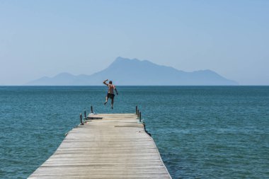 Adam tropikal Ilha Grande okyanusa iskeleden atlama