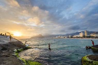 Güzel bulutlar, Rio de Janeiro, Brezilya ile günbatımı zamanı sırasında Ipanema Plajı Slackline üzerinde yürüyen adam