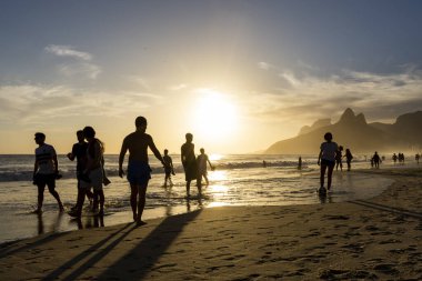 Sahilde futbol oynayan insanlar için Ipanema 'da güzel bir gün batımı manzarası, Rio de Janeiro, Brezilya