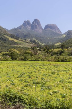 Tres Picos, Rio de Janeiro, Brezilya 'daki yeşil yağmur ormanlarının üzerindeki kayalık dağ zirvelerine güzel bir manzara