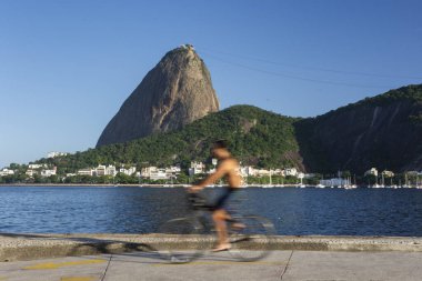 Okyanusun önünde bisiklet süren adamın güzel manzarası ve Sugar Loaf Dağı, Rio de Janeiro, Brezilya