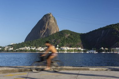 Okyanusun önünde bisiklet süren adamın güzel manzarası ve Sugar Loaf Dağı, Rio de Janeiro, Brezilya