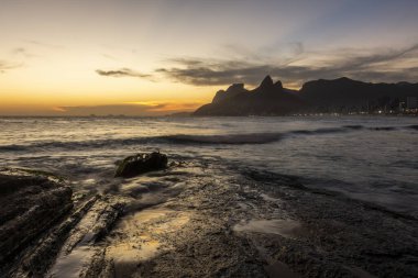 Ipanema Sahili, Rio de Janeiro, Brezilya 'da kayalara vuran dalgalara güzel bir gün batımı manzarası